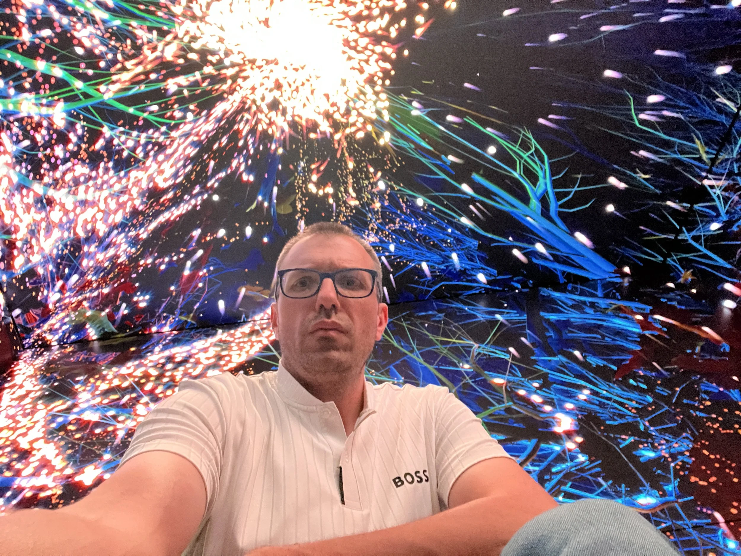 Selfie of Gerard Pastor at Outernet London, with a giant LED screen full of colors behind him.
