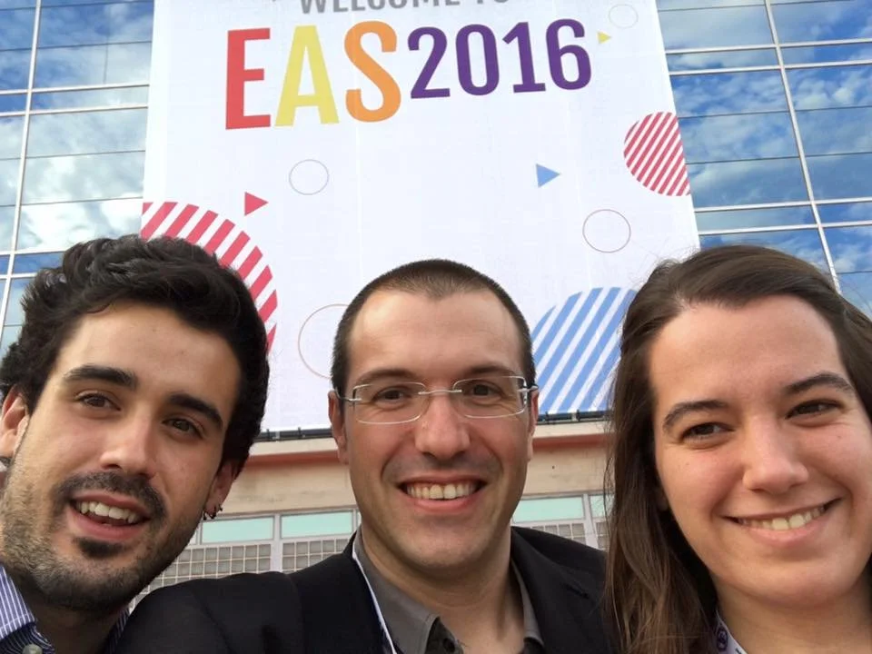 Selfie of Adri Mena, Gerard Pastor, and Marta Urzaiz with a sign in the background reading ‘EAS 2016’ at a trade fair.