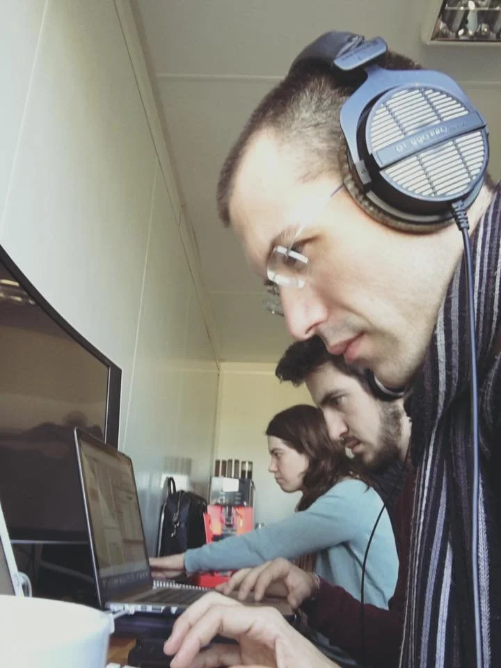 Carles Bernal, Marta Urzaiz, and Gerard Pastor in a room, focused on their computers, working with serious expressions.