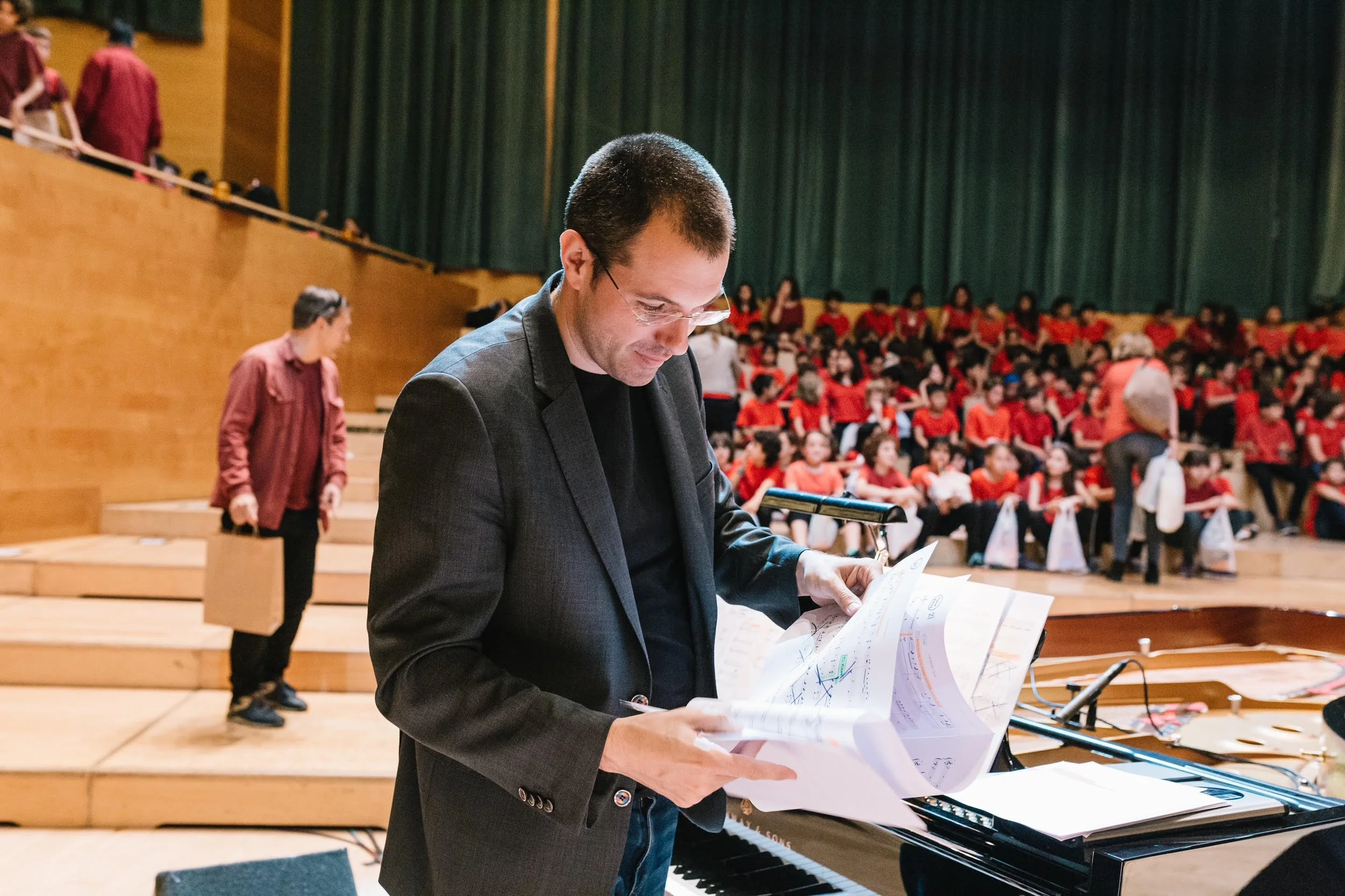 Gerard Pastor reviewing sheet music and smiling on stage at L’Auditori de Barcelona before a concert begins.